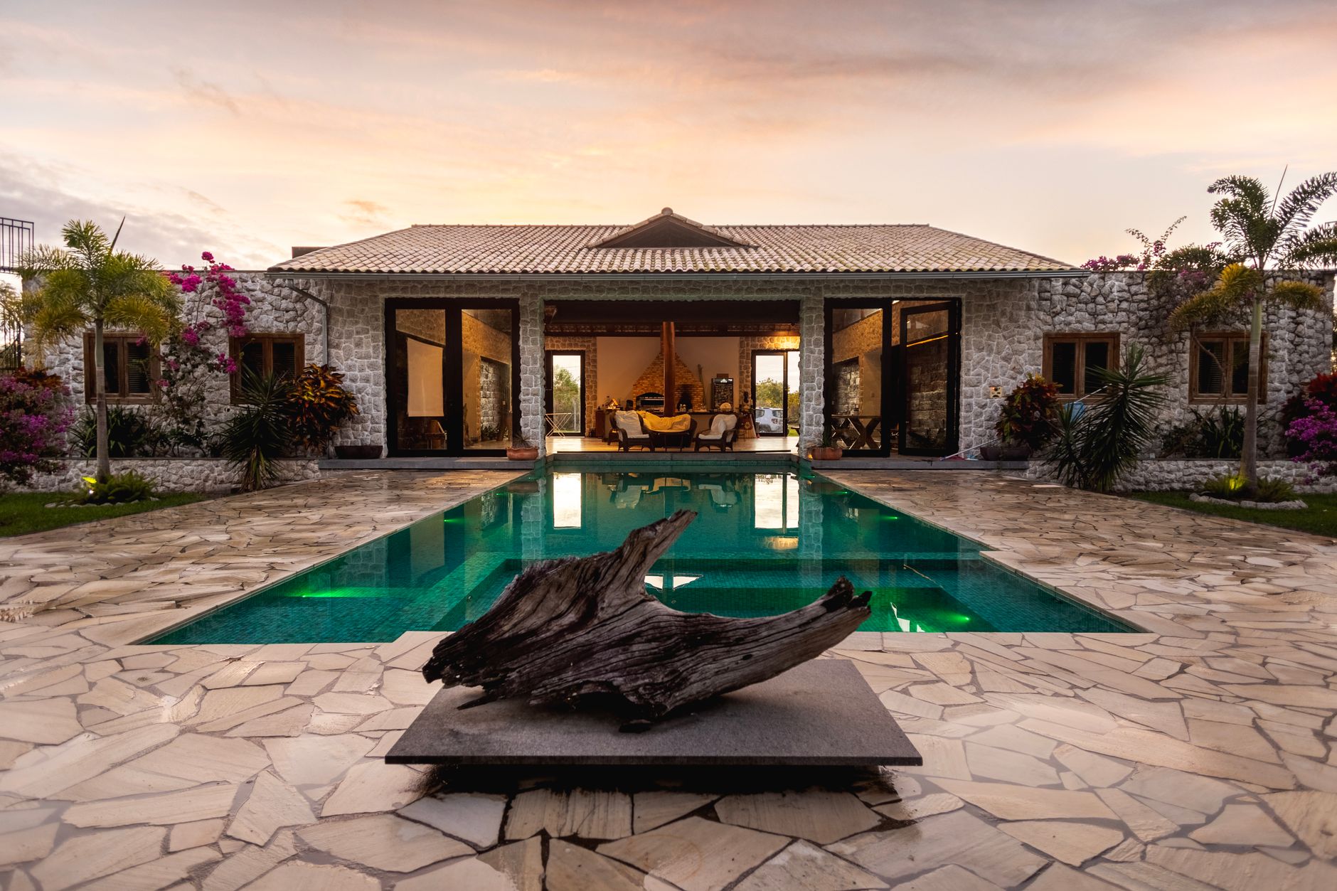 Stone villa at dusk with a lit infinity pool